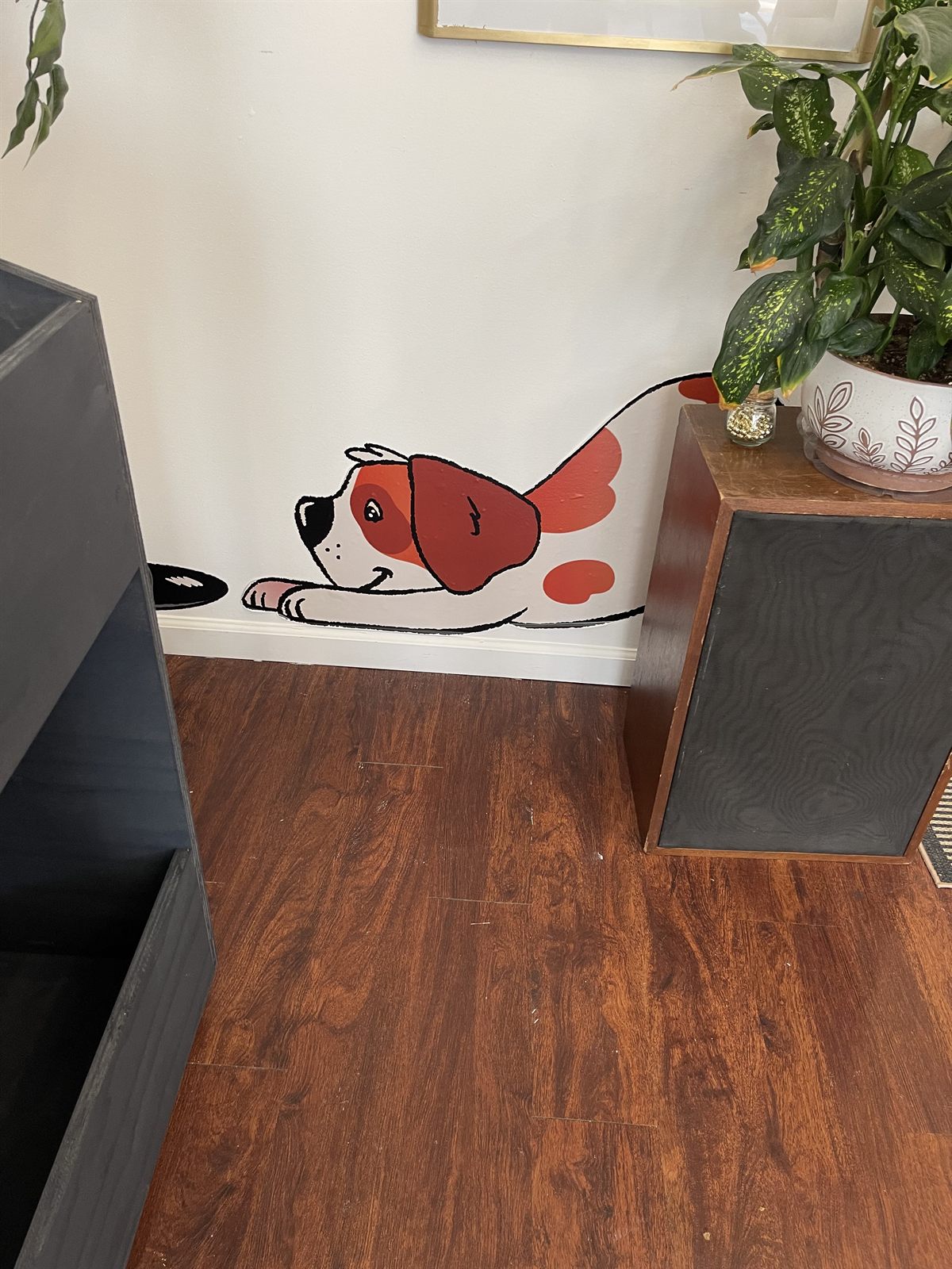 A second mascot graphic near the baseboard, the spaniel pawing at a record between the shop's crates and speakers